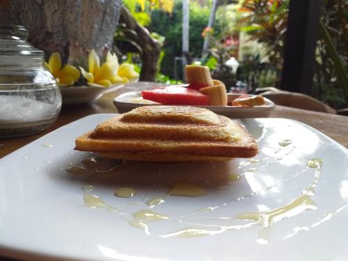 een wit bord met een broodje op een tafel bij Puri Asri Bungalow Ubud in Ubud
