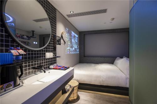 a bedroom with a bed and a sink and a mirror at Fenk Attitude Hotel Guangzhou Railway Station in Guangzhou