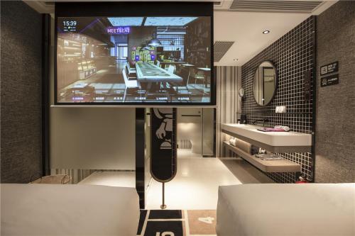 een kamer met een tv aan de muur en een badkamer bij Fenk Attitude Hotel Guangzhou Railway Station in Guangzhou