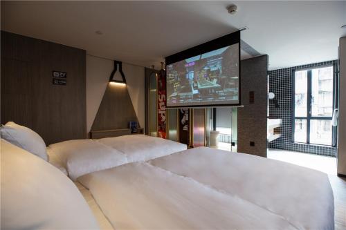 sypialnia z 2 białymi łóżkami i telewizorem w obiekcie Fenk Attitude Hotel Guangzhou Railway Station w Guangzhou