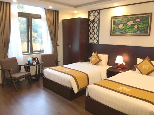 a hotel room with two beds and a table at T&M Luxury Hotel Hanoi in Hanoi