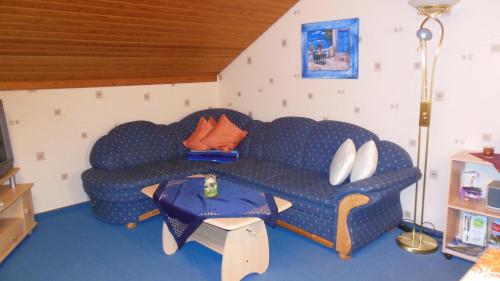 a living room with a blue couch and a table at Landhaus Kathrin in Walkenried