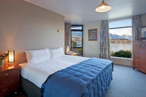 um quarto com uma cama grande e uma janela grande em Apartments at Spinnaker Bay em Queenstown