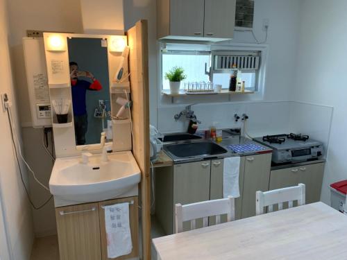 a small kitchen with a sink and a mirror at GOLDHOUSE Shinosaka 305 in Osaka