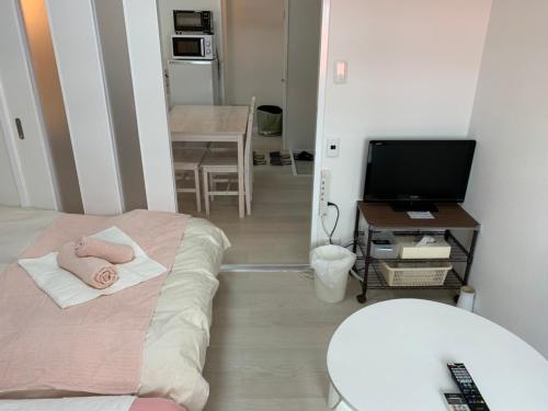 a small room with a bed and a table with a television at GOLDHOUSE Shinosaka 305 in Osaka