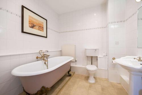 a bathroom with a tub and a toilet and a sink at Makeney Hall Hotel in Derby