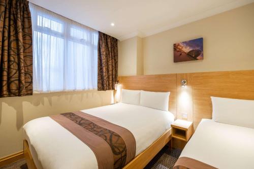 um quarto de hotel com duas camas e uma janela em Comfort Inn Hyde Park em Londres