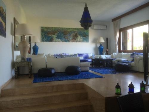 sala de estar con sofás blancos y alfombra azul en Villa Eden Park sur la plage, en Fnidek