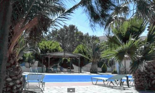 a swimming pool with tables and chairs and palm trees at Orama Hotel in Sígrion