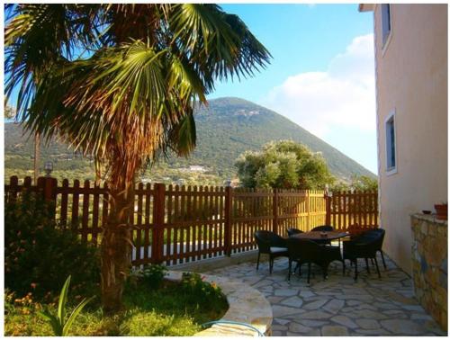 a patio with a table and chairs and a palm tree at Iriana Village Inn in Stavros