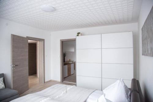 a bedroom with a white bed and a white cabinet at Spitaler Apartments in Kirchberg am Walde