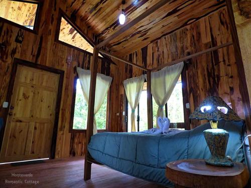 um quarto com um sofá azul numa cabina de madeira em Monteverde Romantic Cottage em Monteverde