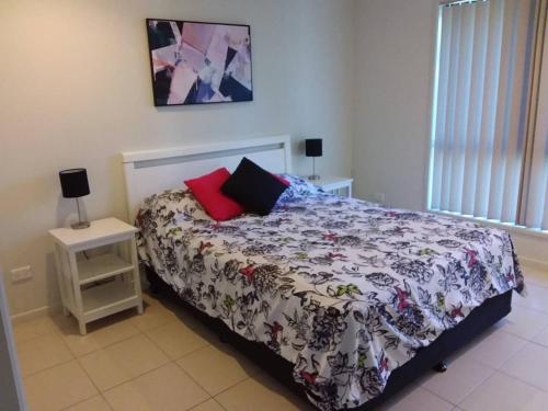 a bedroom with a bed with a flowered blanket and two pillows at Waratah and Wattle Apartments in Maryborough