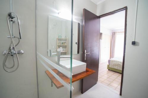 a bathroom with a sink and a glass shower door at Blue View Seaside Luxury Apartments in Ixia