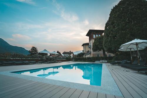a swimming pool with an umbrella and a house at Villa Vitali - Bellagio in Bellagio