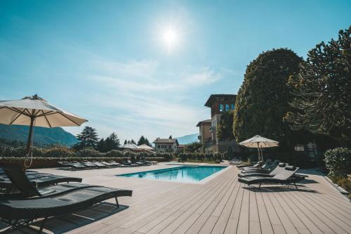 a pool with chairs and umbrellas next to a building at Villa Vitali - Bellagio in Bellagio
