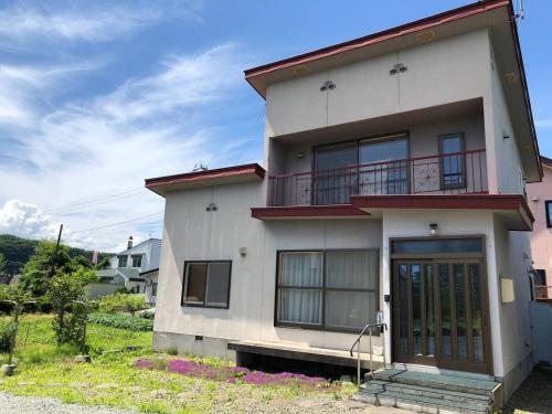 a white house with a balcony on top of it at 旭川貸切一軒家プラスティ in Asahikawa