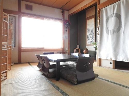 una sala da pranzo con tavolo, sedie e finestra di 旭川貸切一軒家プラスティ a Asahikawa