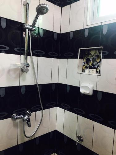 a shower in a bathroom with black and white tiles at Italy Condotel Darasa in Tanauan