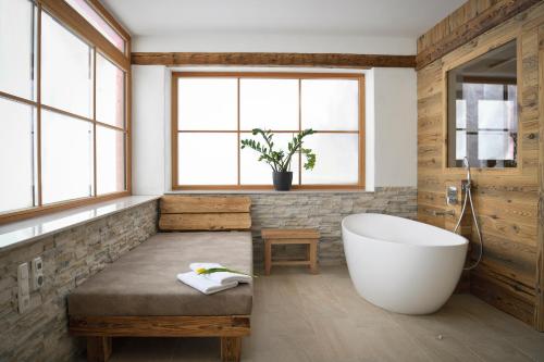 a bathroom with a large tub and a bench and windows at Ferienhaus Almruhe in Schwanberg