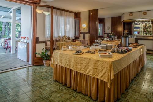 Hotel Adriaco في غرادو: غرفة بها عدة طاولات عليها طعام