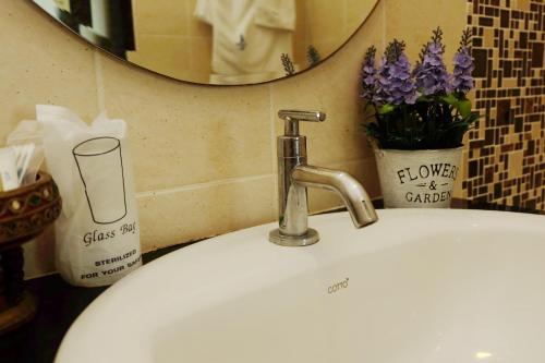 a bathroom sink with a faucet and a mirror at Calypso Patong Hotel in Patong Beach