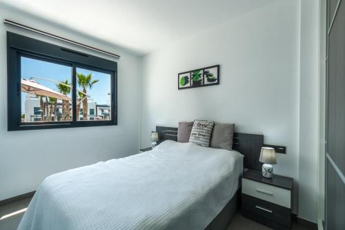 sypialnia z białym łóżkiem i oknem w obiekcie Oasis Beach F 3003 w mieście Playas de Orihuela