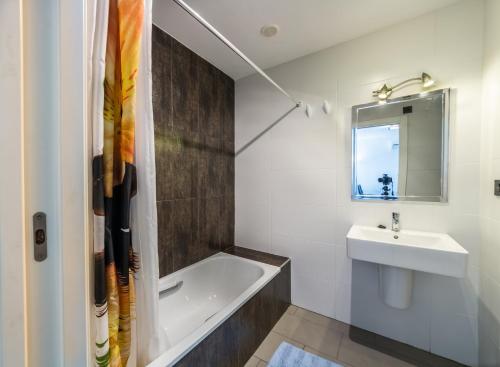 W łazience znajduje się umywalka, wanna i lustro. w obiekcie Oasis Beach F 3003 w mieście Playas de Orihuela