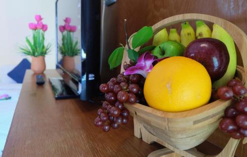 a wooden bowl of fruit on a table at Calypso Patong Hotel in Patong Beach
