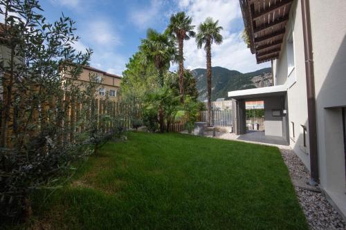 een tuin met palmbomen en een gebouw bij Le Palme Rooms & Breakfast in Trento