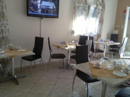 un restaurant avec des tables et des chaises ainsi qu'une télévision murale. dans l'établissement To Giouli, à Vólos