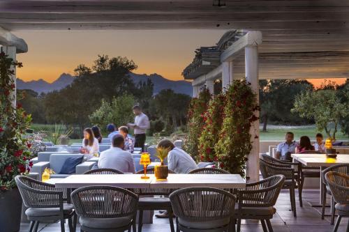 a group of people sitting at tables on a patio at Li Neuli Country Club in San Pantaleo