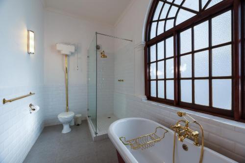 Un baño con bañera y ducha y un inodoro. en Esperanza Guest House, en Ciudad del Cabo
