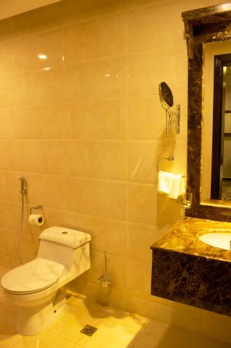 a bathroom with a toilet and a sink and a mirror at Rona Al Khobar Hotel in Al Khobar