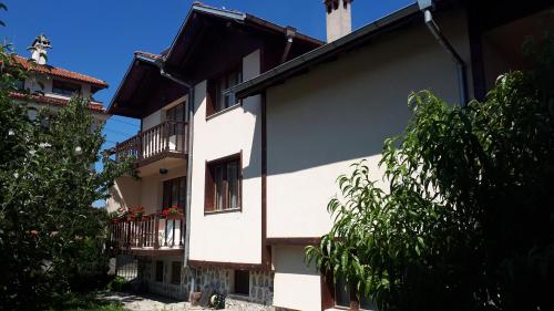 a white building with balconies and a tree at Тодор Прегьов in Bansko