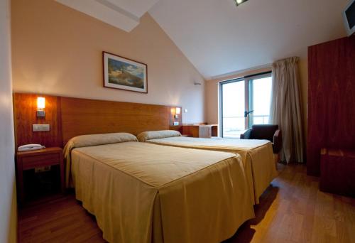 a hotel room with a large bed and a window at Hotel O Noso Portosin in Portosin