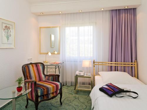 a hotel room with a bed and a chair and a table at Hotel Palmenhof in Frankfurt/Main