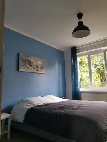 une chambre bleue avec un lit et une fenêtre dans l'établissement Face aux remparts, à Boulogne-sur-Mer