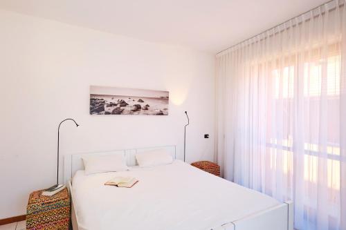 a white bedroom with a white bed and a window at Lario View Apartment in Acquaseria