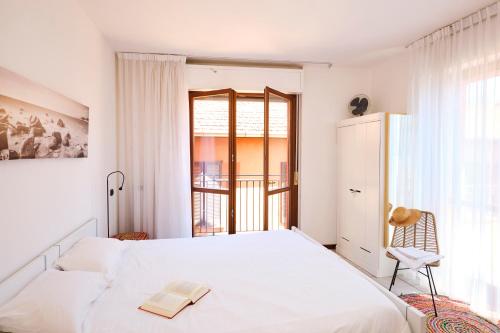 a white bedroom with a bed and a window at Lario View Apartment in Acquaseria