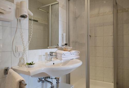 a white bathroom with a sink and a shower at Pension zur Sonne in Illmitz