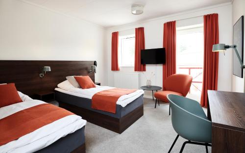 a hotel room with two beds and a chair at Montra Odder Parkhotel in Odder