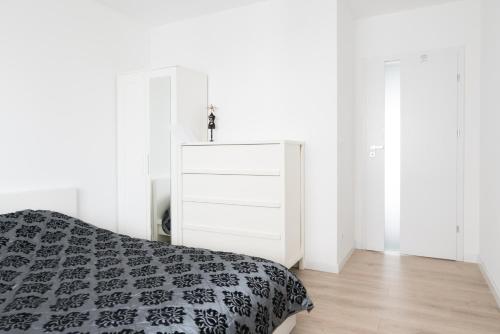 a white bedroom with a bed and a dresser at Republiki Korczakowskiej Ferienwohnung in Krakow