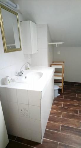 une salle de bain blanche avec un lavabo et un miroir dans l'établissement Gîte Valentin, à Dompierre-sur-Besbre