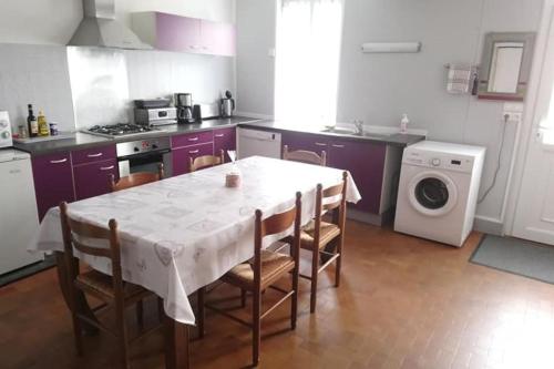 une cuisine avec une table et des chaises et une cuisine avec des placards violets dans l'établissement Gîte Valentin, à Dompierre-sur-Besbre