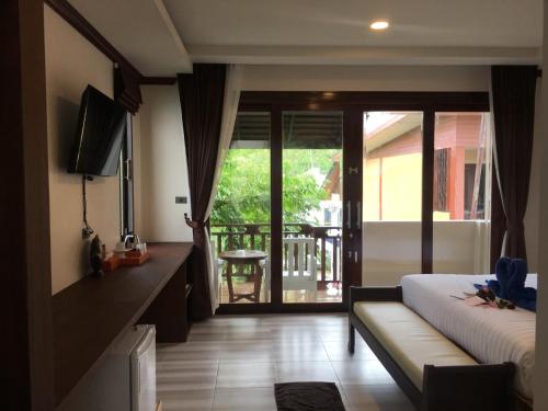a bedroom with a bed and a television and a balcony at Wind Beach Resort in Koh Tao