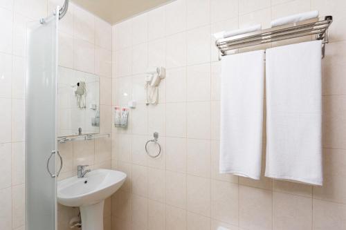 ein weißes Bad mit einem Waschbecken und einer Dusche in der Unterkunft VOYAGE HOTEL in Fargʻona