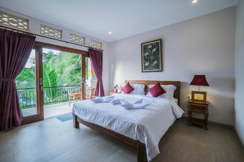 um quarto com uma cama grande e uma varanda em Jero Griya Ubud em Ubud