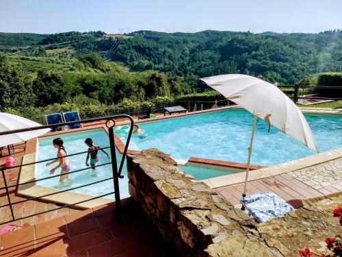 a swimming pool with people playing in the water at Borgo La Casaccia in Montaione