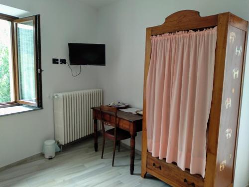 Cette chambre dispose d'un bureau, d'une télévision et d'un bureau avec une fenêtre. dans l'établissement Chez Bonjour, à Villar Pellice